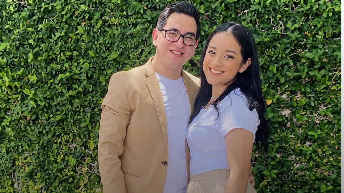 Joven y adulto sonrientes frente a muro de plantas verdes. — memphisnoticias.com