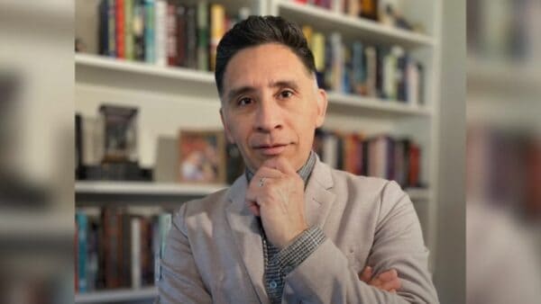 EDITORIAL | Memphis no necesita más miedo: necesita seguridad con derechos y rendición de cuentas at Memphis Noticias | 12 Hombre con barba y camisa gris en biblioteca, pensativo. — memphisnoticias.com