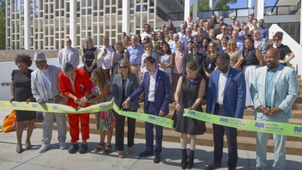 Funcionarios y representantes del metal museum cortan una cinta verde frente al nuevo edificio del museo en overton park.