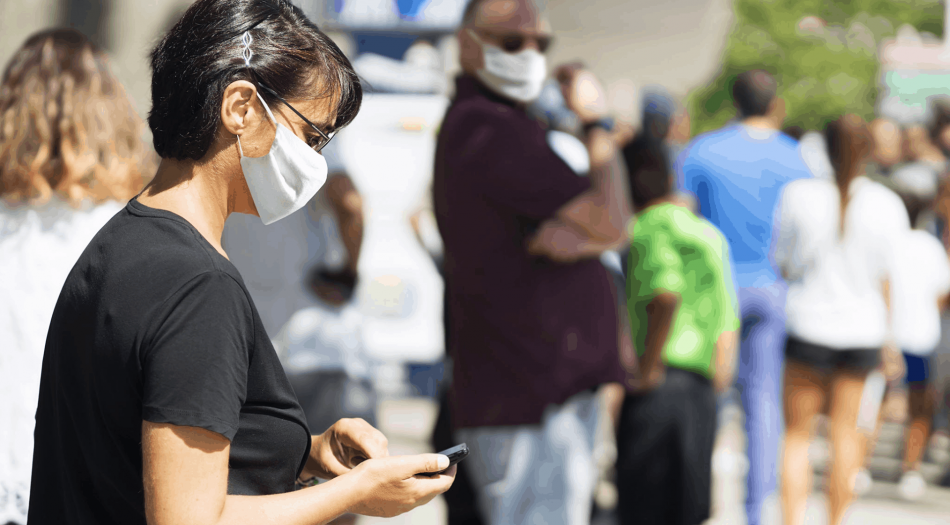 woman wearing mask looking at phone